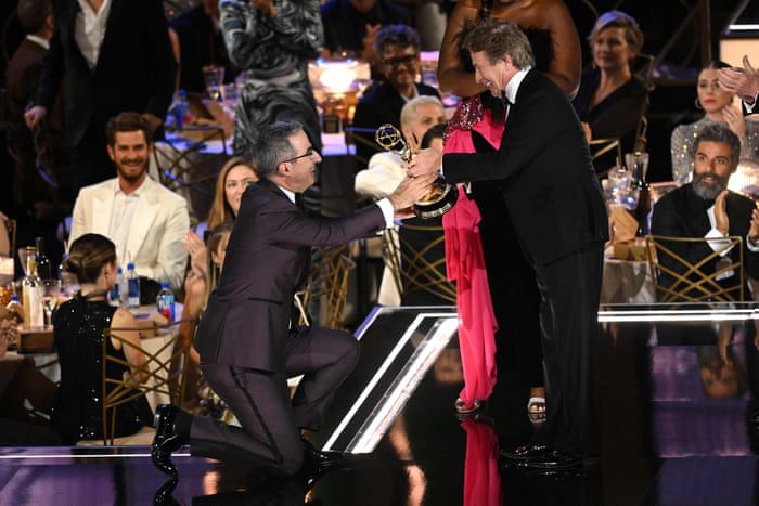 John Oliver kniet nieder, als er den Preis für die beste Variety-Talk-Serie entgegennimmt.