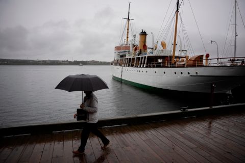 Ein Fußgänger schützt sich mit einem Regenschirm, als er am Freitag an der Küste von Halifax entlang geht.